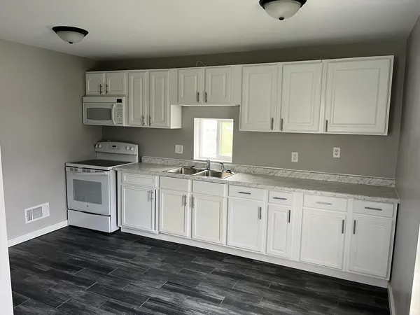 a kitchen with granite countertop white cabinets and white appliances