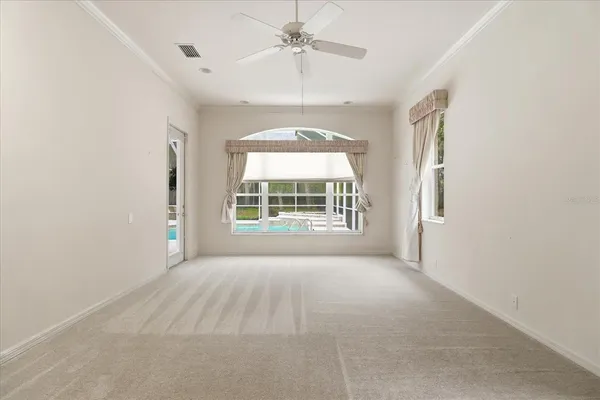 an empty room with windows and chandelier fan