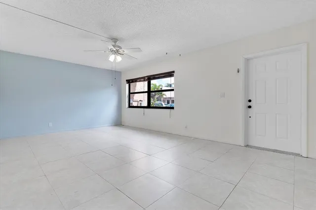 an empty room with windows and ceiling fan