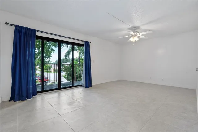 an empty room with a chandelier fan and windows