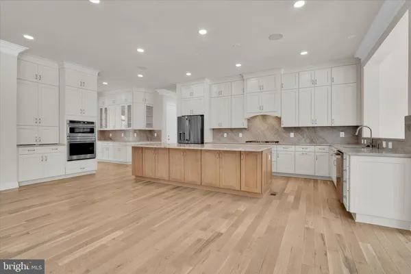 a large kitchen with stainless steel appliances granite countertop a refrigerator and a view of living room