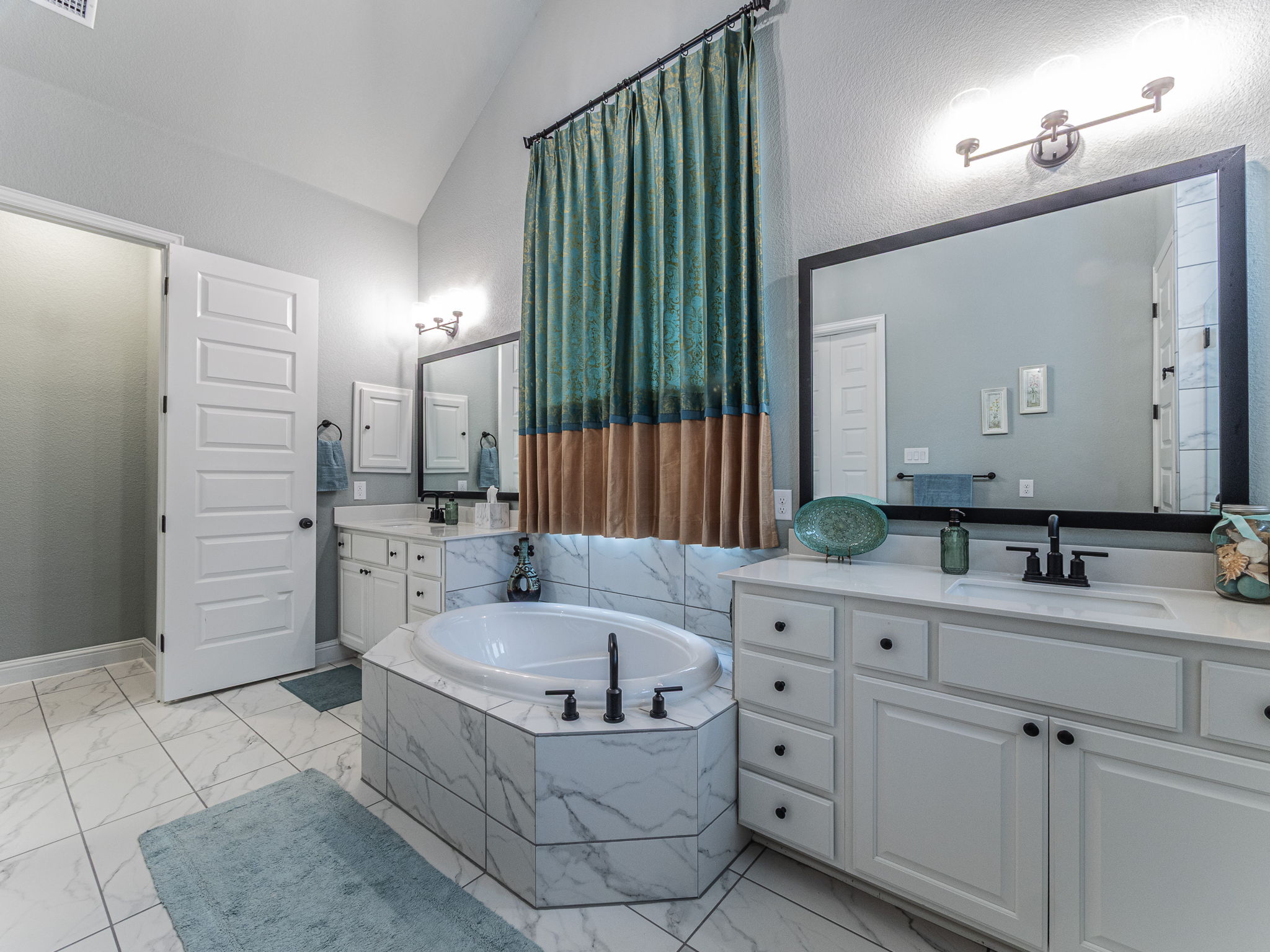 112 Hollytree Court Georgetown, TX 78628 - Photo 15 of 40 Bathroom featuring two vanities, vaulted ceiling, light marble finish flooring, and a bath