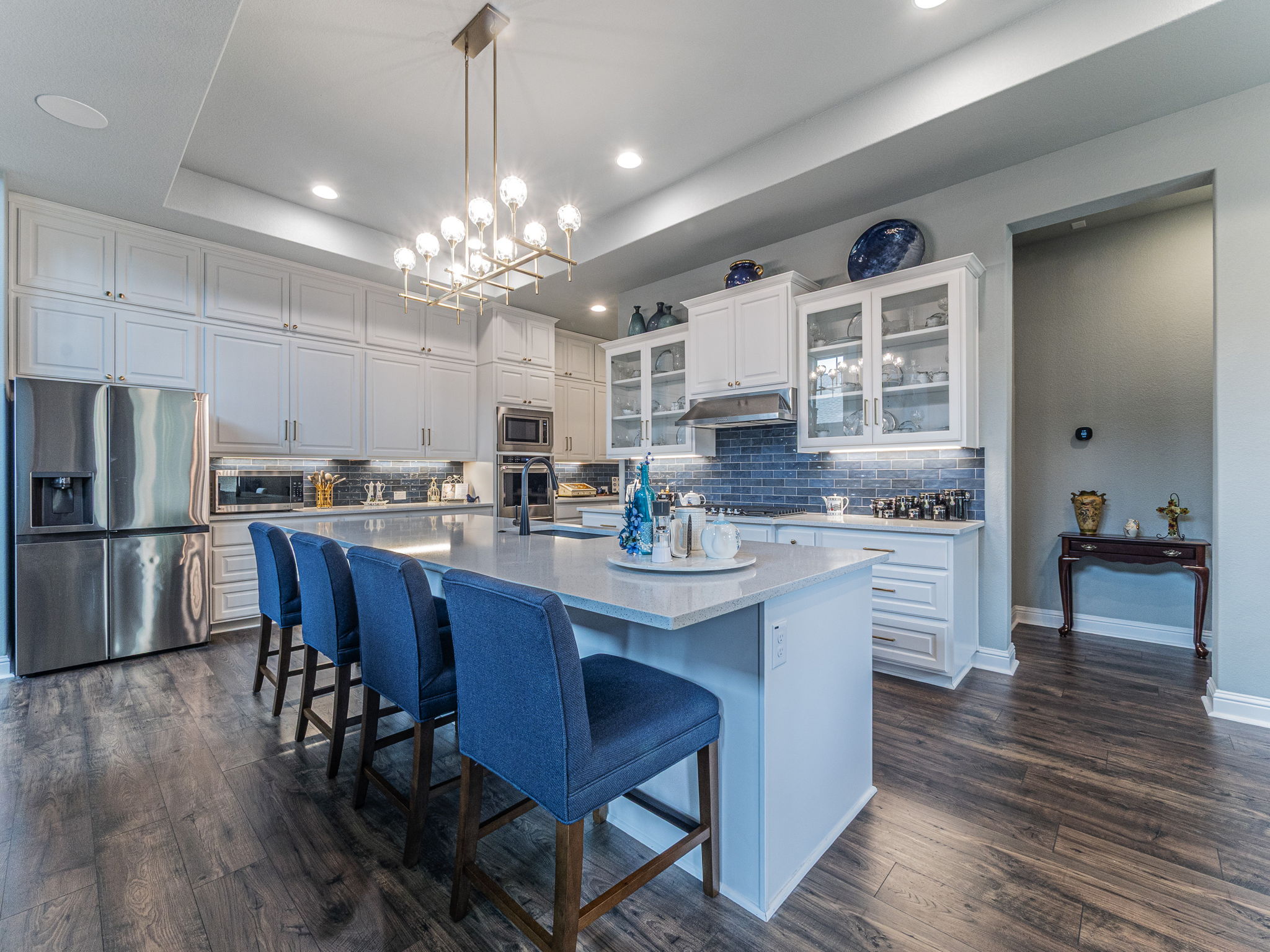 112 Hollytree Court Georgetown, TX 78628 - Photo 9 of 40 Kitchen featuring glass insert cabinets, stainless steel appliances, white cabinetry, decorative backsplash, and a kitchen island with sink