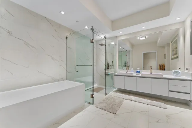 a large white bathroom with a large mirror vanity and a shower