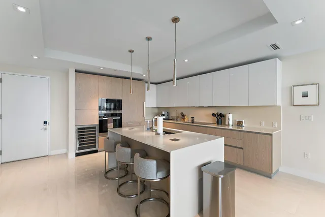 a kitchen with a stove a sink a kitchen island with chairs and wooden cabinets