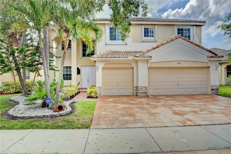 3863 Falcon Ridge Circle Weston, FL 33331 - Photo 9 of 52 a view of a white house next to a yard and palm trees
