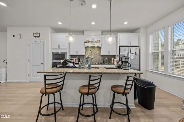 a kitchen with stainless steel appliances a table chairs refrigerator and microwave