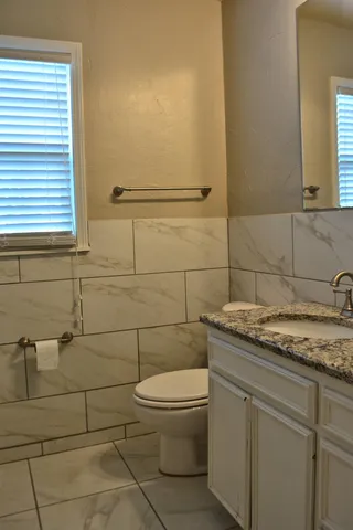 a bathroom with a granite countertop toilet a sink and a mirror