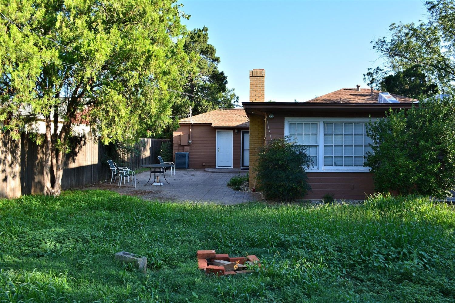 3213 26th Street Lubbock, TX 79410 - Photo 18 of 20 a backyard of a house with table and chairs under an umbrella