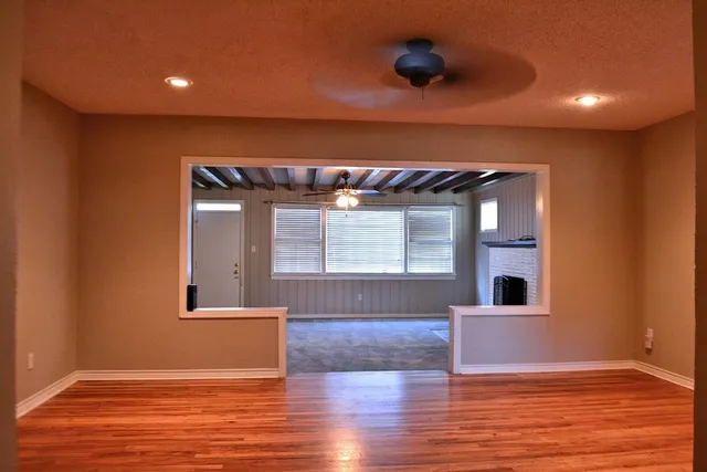 a view of an empty room with wooden floor and a window