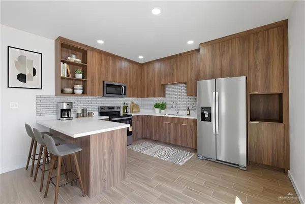 a kitchen with a refrigerator a stove top oven a sink dishwasher and wooden cabinets with wooden floor