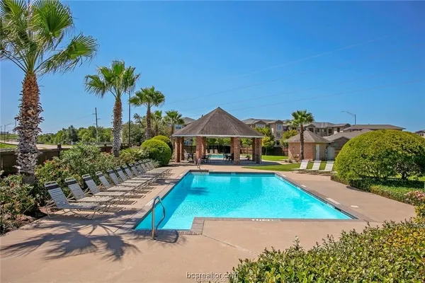 a view of a swimming pool with lawn chairs under an umbrella