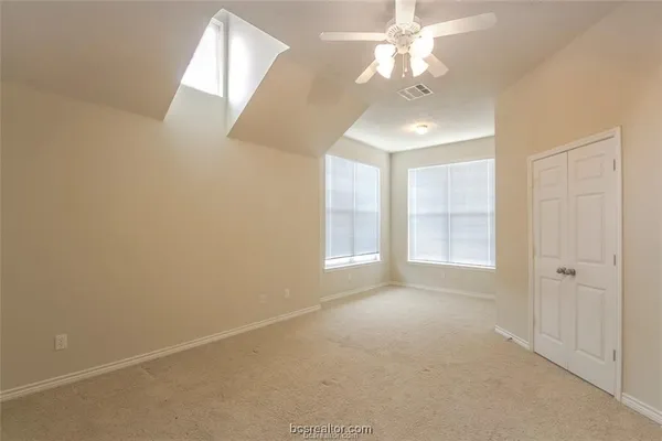 an empty room with chandelier fan and windows