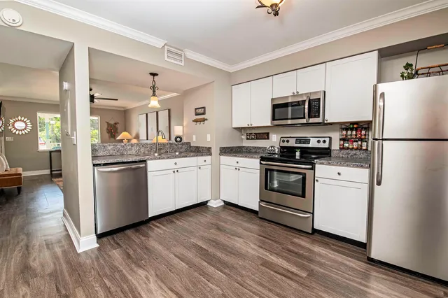 a kitchen with white cabinets stainless steel appliances and wooden floor