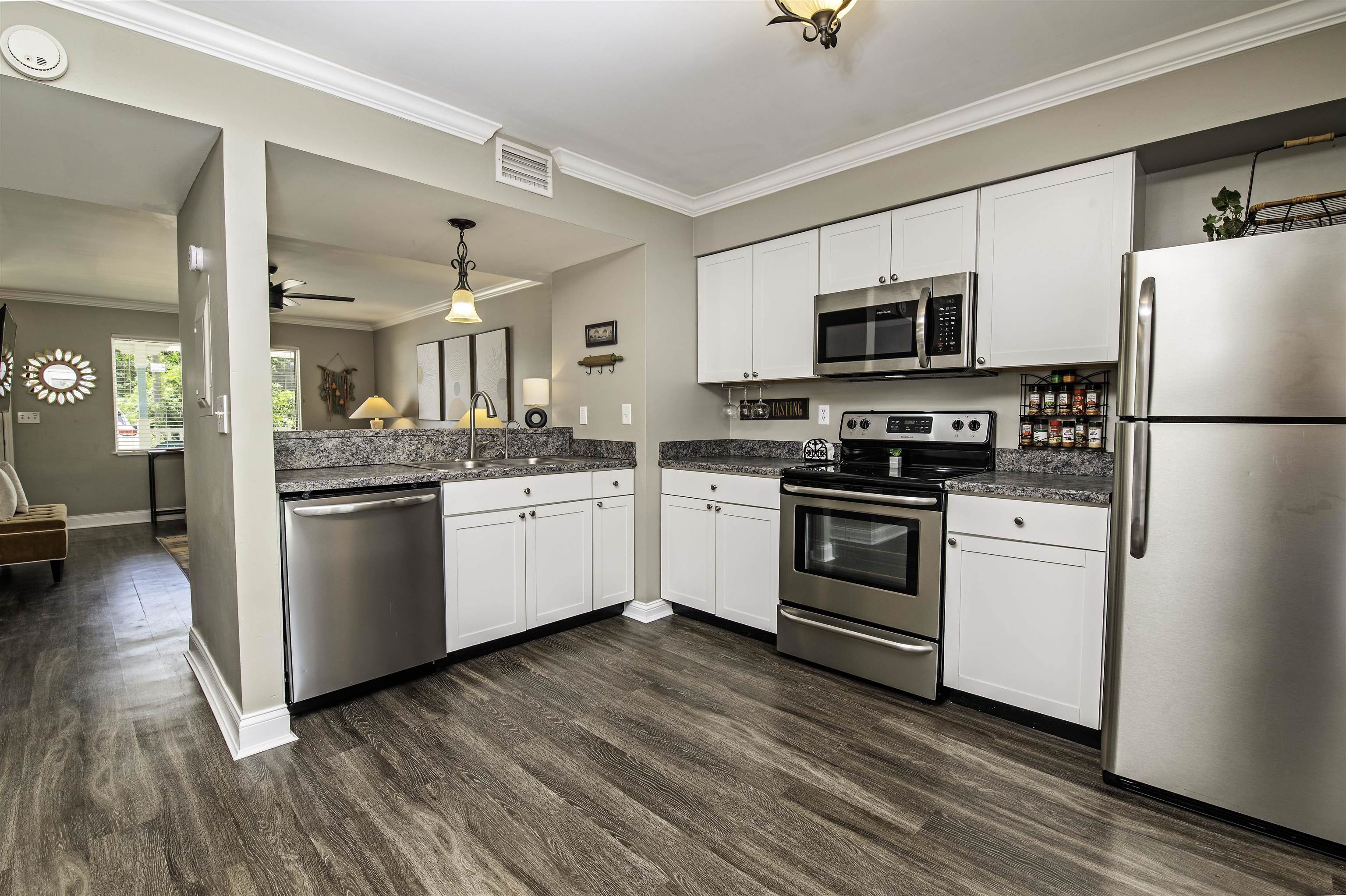 6452 Madison Street St. Augustine, FL 32080 - Photo 8 of 27 a kitchen with white cabinets stainless steel appliances and wooden floor