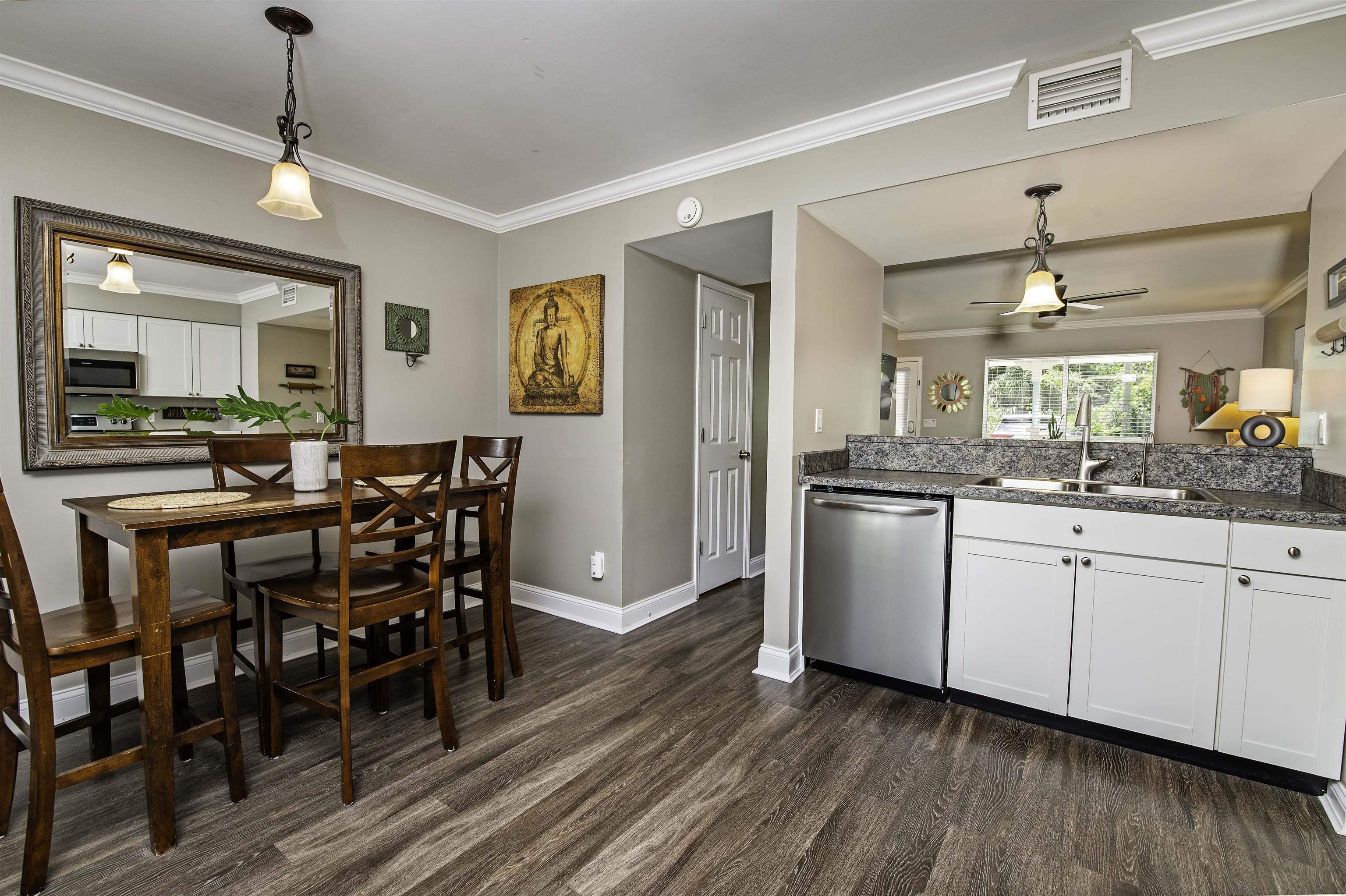 6452 Madison Street St. Augustine, FL 32080 - Photo 9 of 27 a kitchen with stainless steel appliances granite countertop a dining table chairs and white cabinets