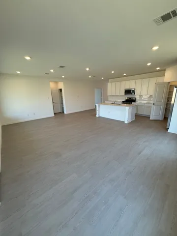 a view of empty room with kitchen and window
