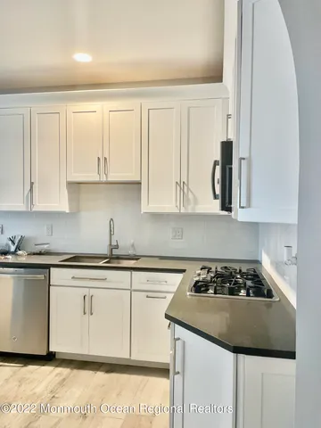 a kitchen with stainless steel appliances granite countertop a stove a sink and white cabinets