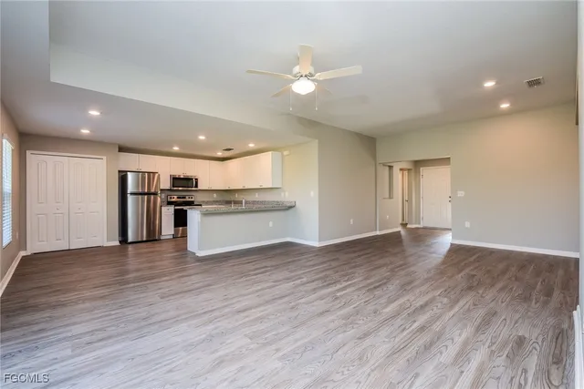 a view of an empty room with window and wooden floor