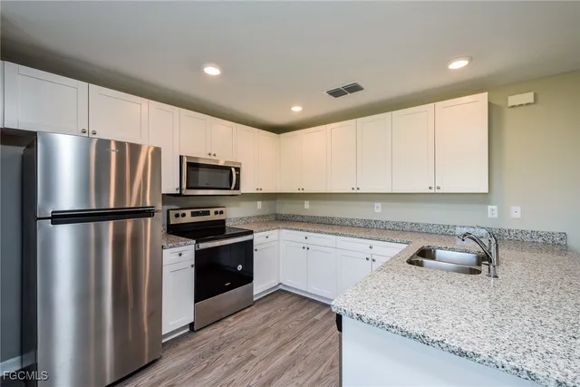 a kitchen with stainless steel appliances granite countertop a sink stove and refrigerator