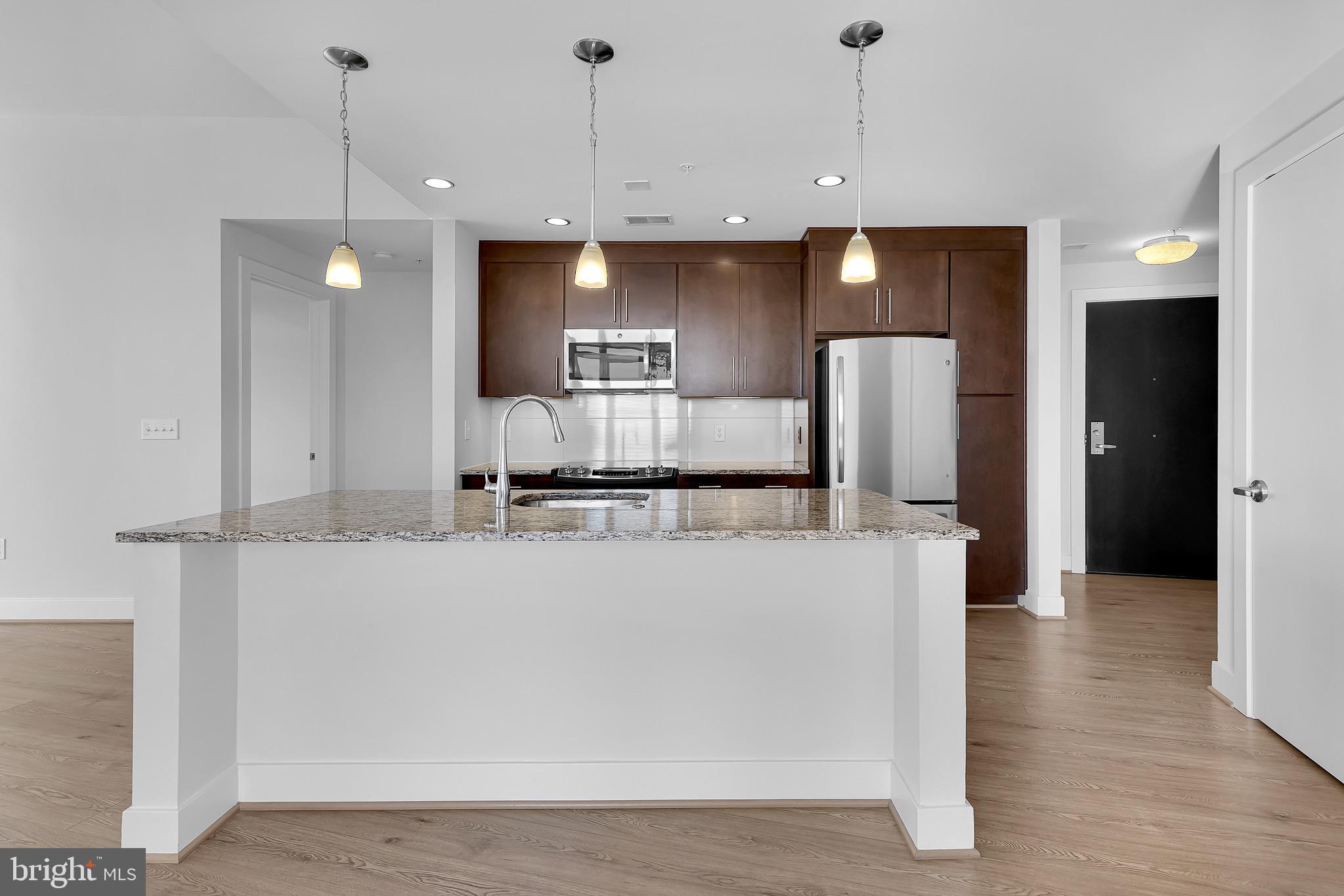 a view of a kitchen with kitchen island a counter top space stainless steel appliances and a ceiling fan
