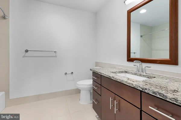 a bathroom with a granite countertop sink a toilet and mirror