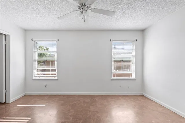 an empty room with a chandelier fan and closet area