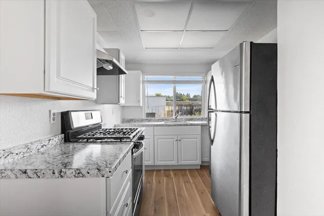 a kitchen with stainless steel appliances granite countertop a refrigerator and a stove top oven