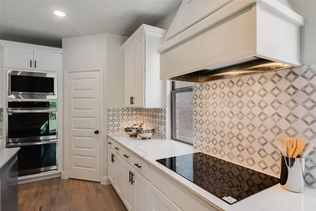 a kitchen with white cabinets and appliances