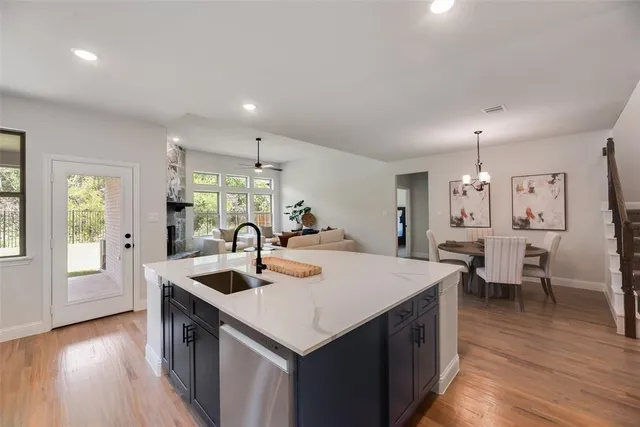 a open kitchen with stainless steel appliances granite countertop a sink dishwasher and a dining table with wooden floor