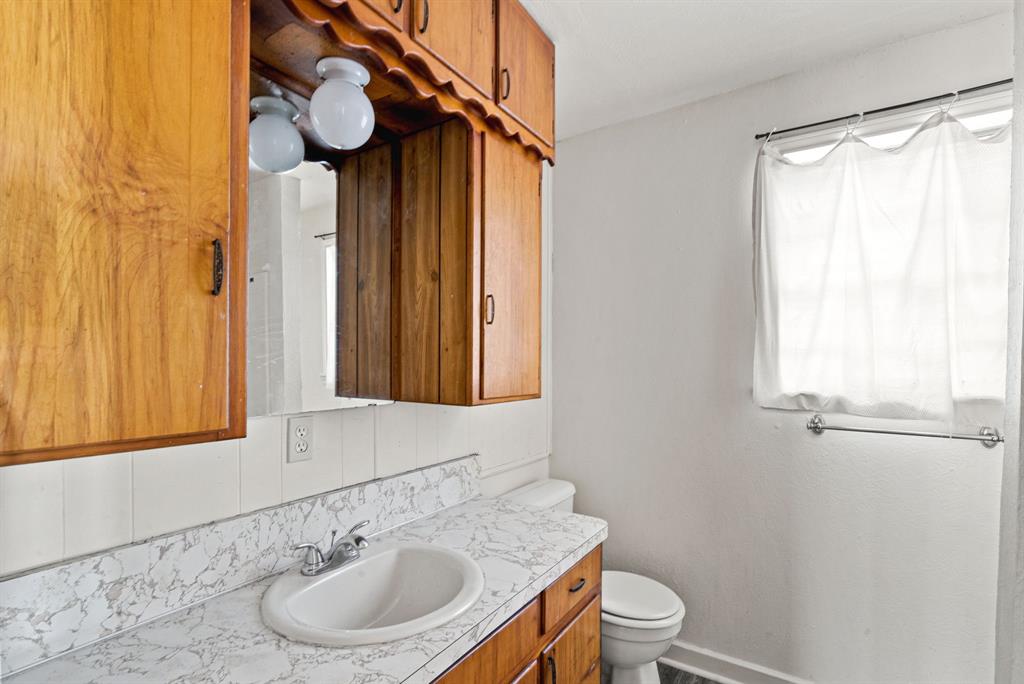 1040 Clinton Avenue Stephenville, TX 76401 - Photo 18 of 26 a bathroom with a toilet a sink and a mirror