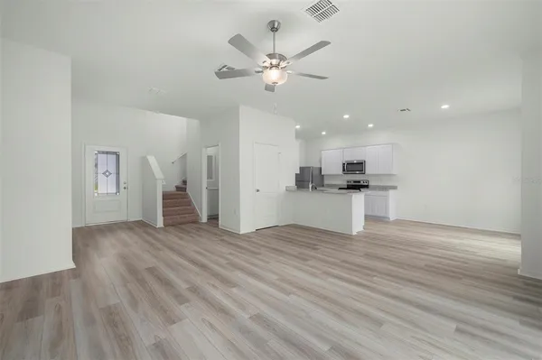 a view of an empty room with wooden floor and a ceiling fan