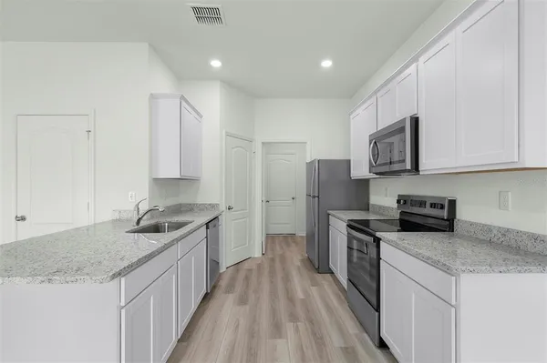 a kitchen with stainless steel appliances granite countertop a sink stove and refrigerator