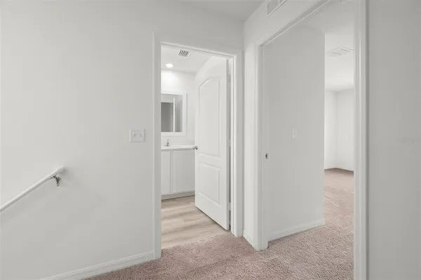 a view of a hallway with closet and a bathroom