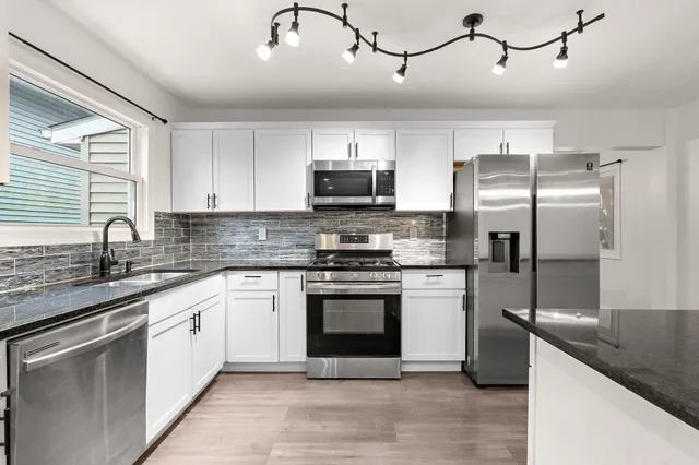 a kitchen with stainless steel appliances granite countertop a stove sink and refrigerator