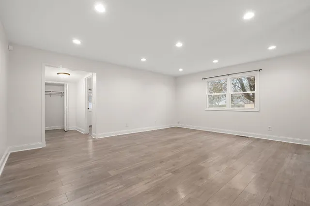 an empty room with wooden floor and window