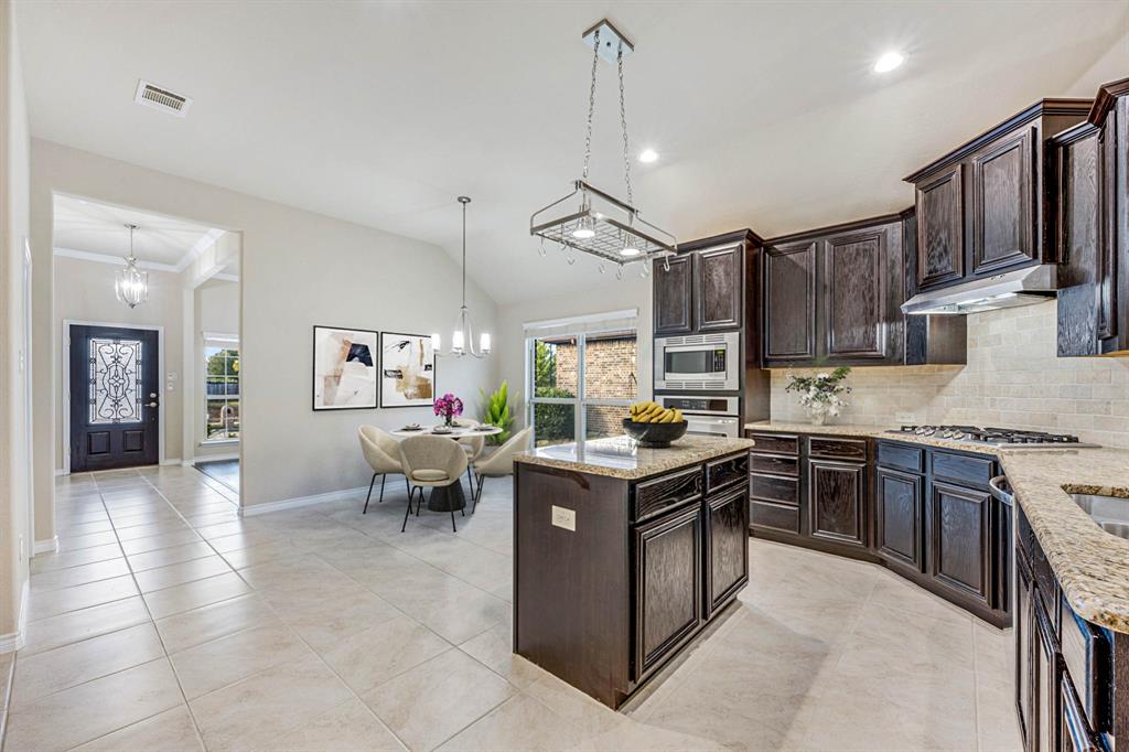 5022 Hidden Creek Road Garland, TX 75043 - Photo 8 of 36 a kitchen with stainless steel appliances granite countertop a stove top oven a sink dishwasher a dining table and chairs with wooden cabinets
