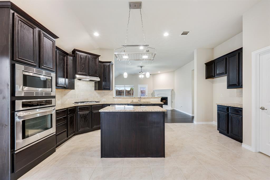 5022 Hidden Creek Road Garland, TX 75043 - Photo 9 of 36 a large kitchen with stainless steel appliances kitchen island granite countertop a stove top oven a sink dishwasher a refrigerator and a fireplace with wooden floor