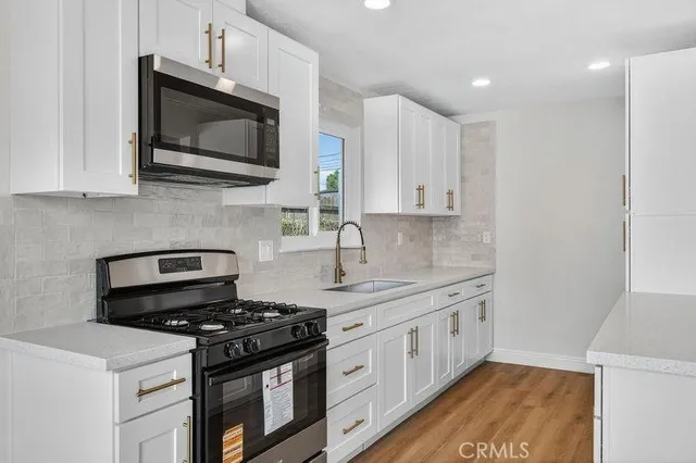 a kitchen with stainless steel appliances a sink dishwasher a stove and a microwave oven on granite countertops