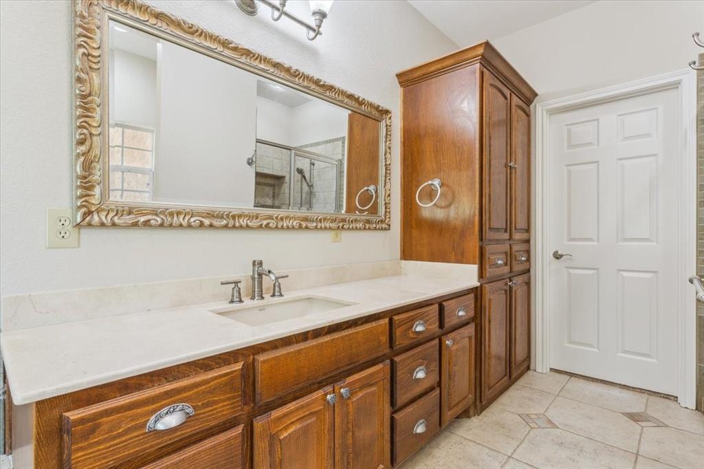 3439 Willow Branch Road McGregor, TX 76657 - Photo 16 of 40 a bathroom with a granite countertop sink a mirror a vanity and a bathtub