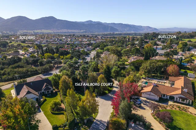 an aerial view of residential houses with outdoor space and trees