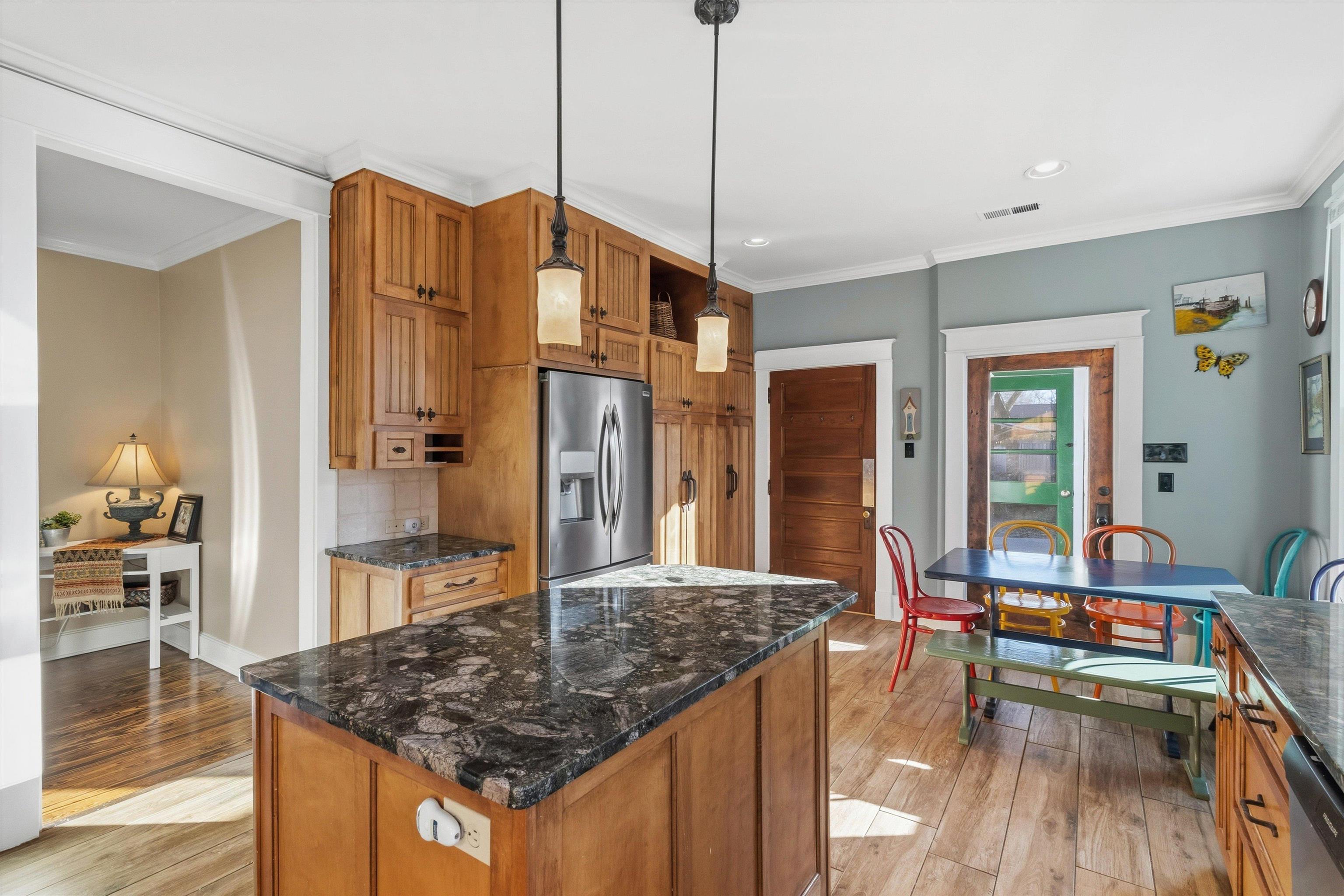 30 Front Street Rossville, TN 38066 - Photo 21 of 39 Kitchen with brown cabinets, hanging light fixtures, dark stone countertops, a kitchen island, and appliances with stainless steel finishes