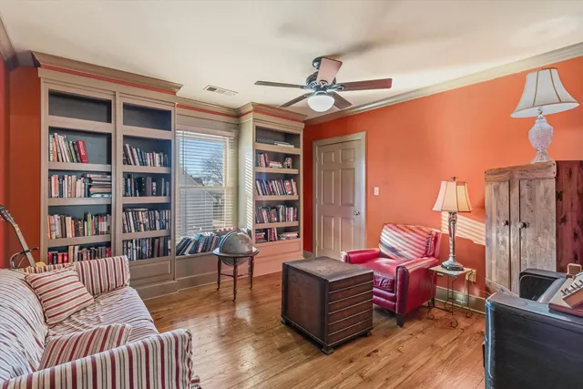 a living room with furniture a bookshelf and a window