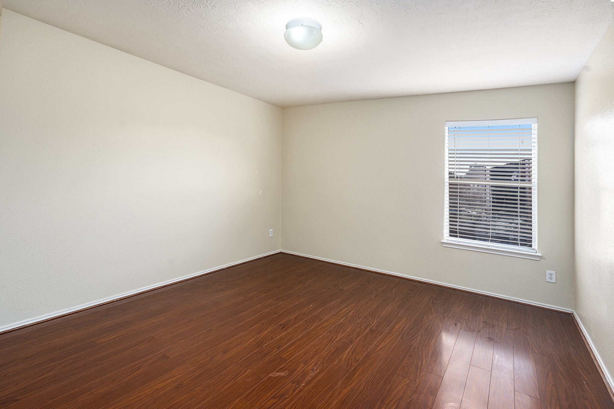 18227 Thicket Grove Road Houston, TX 77084 - Photo 19 of 28 an empty room with wooden floor and windows