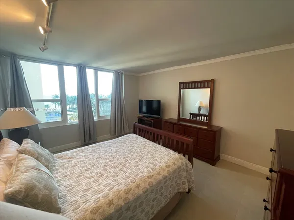 a bedroom with a large bed and a flat tv screen on dresser
