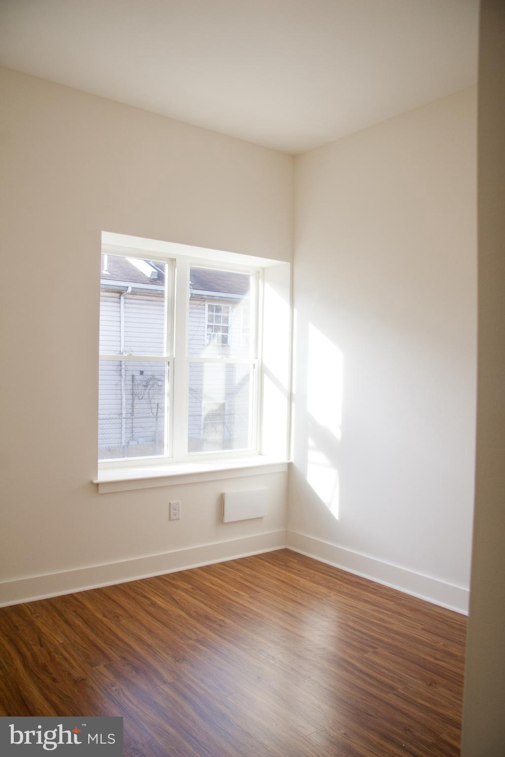 6040 Market Street, Unit 3 Philadelphia, PA 19139 - Photo 5 of 9 an empty room with wooden floor and windows