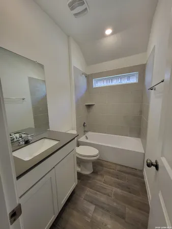 a bathroom with a granite countertop sink toilet a large mirror a bathtub and shower
