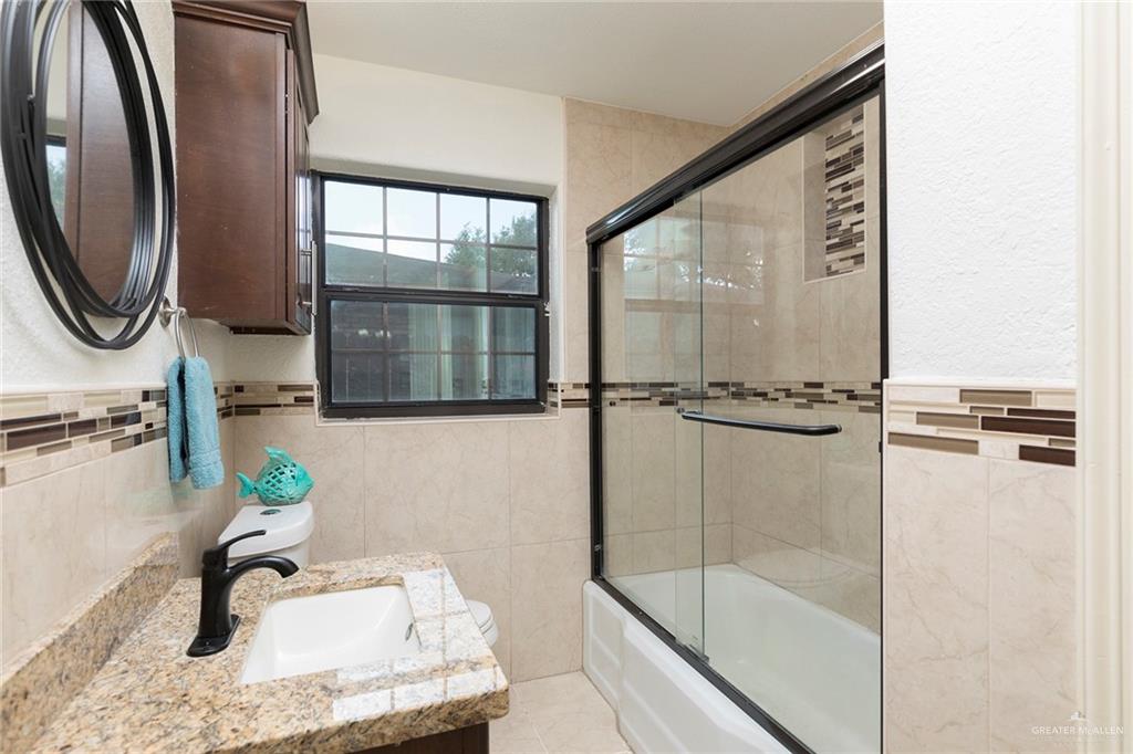 1312 North 5th Street McAllen, TX 78501 - Photo 19 of 25 The third bathroom features a shower-tub combo, filled with natural light. It’s both functional and inviting for daily use.