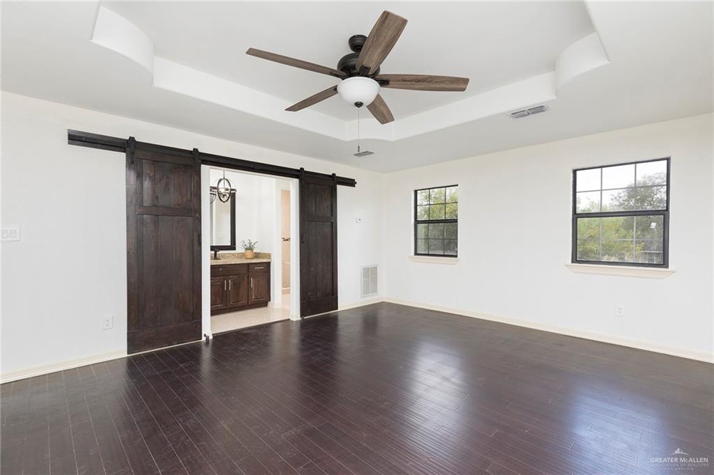 1312 North 5th Street McAllen, TX 78501 - Photo 10 of 25 The primary bedroom is a nice size, featuring stunning barn doors that add a touch of charm. Pretty yard view and hardwood floors!