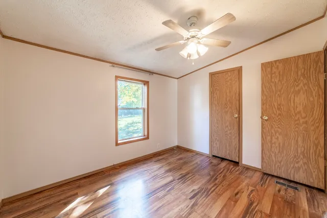 a view of an empty room with wooden floor and a window